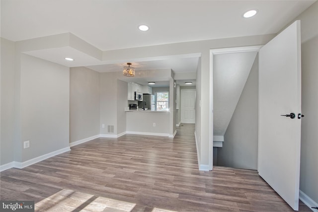 unfurnished living room with recessed lighting, wood finished floors, and baseboards