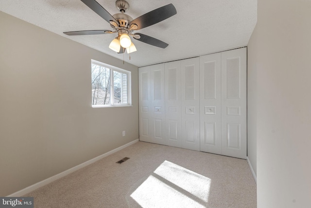 unfurnished bedroom with visible vents, baseboards, a textured ceiling, and carpet flooring