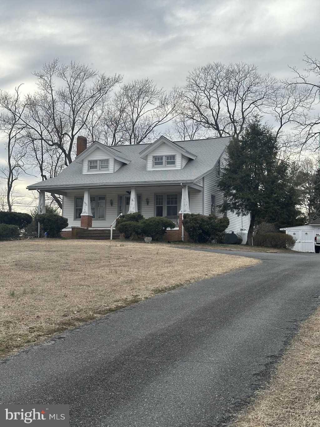 view of front facade with covered porch, a front lawn, and a shingled roof