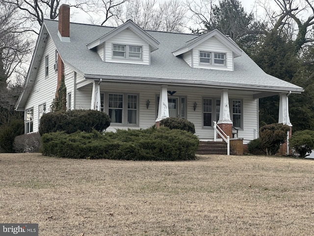 view of front of property with a porch, a shingled roof, and a front yard