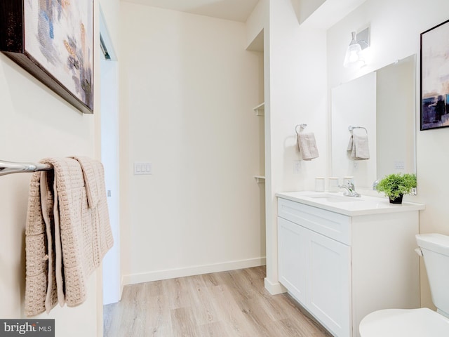 bathroom with baseboards, toilet, wood finished floors, and vanity