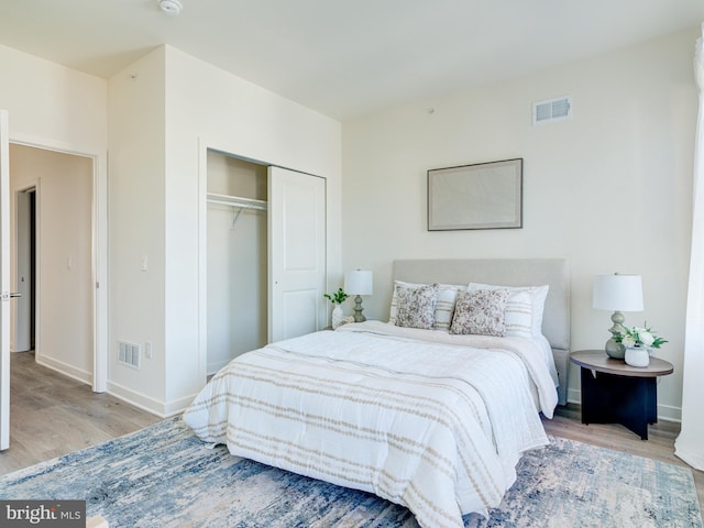 bedroom with a closet, visible vents, and wood finished floors