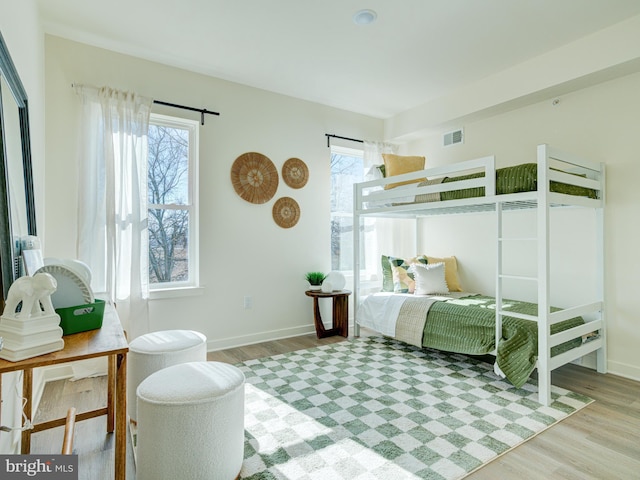 bedroom with visible vents, multiple windows, baseboards, and wood finished floors