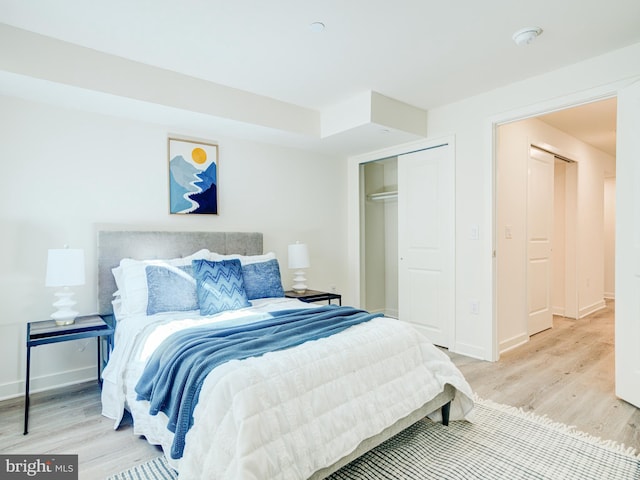 bedroom featuring baseboards, a closet, and light wood finished floors