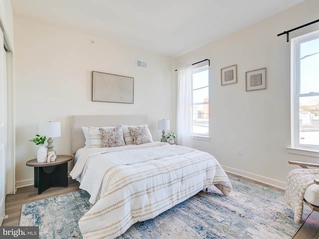 bedroom featuring wood finished floors, visible vents, and baseboards