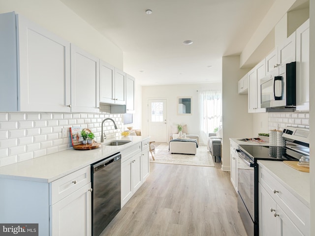 kitchen featuring light wood-style flooring, a sink, white cabinetry, dishwashing machine, and stainless steel electric range oven