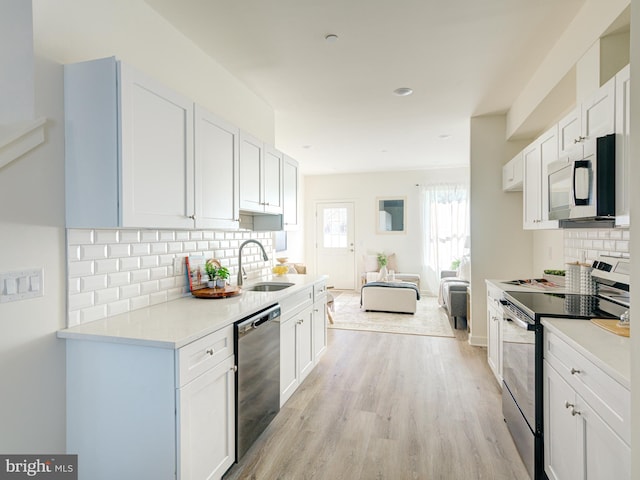 kitchen featuring light wood-type flooring, a sink, white cabinetry, appliances with stainless steel finishes, and light countertops