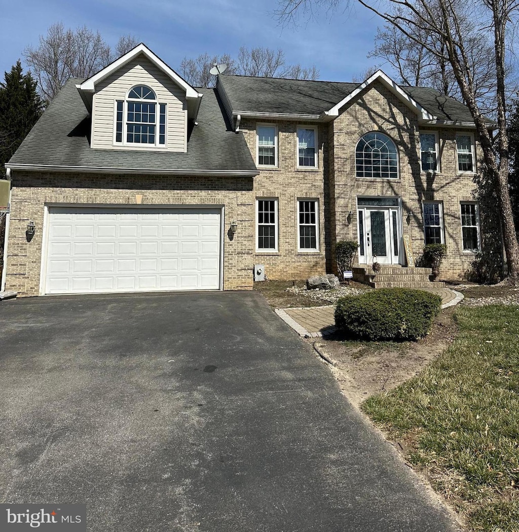 colonial inspired home with aphalt driveway and brick siding