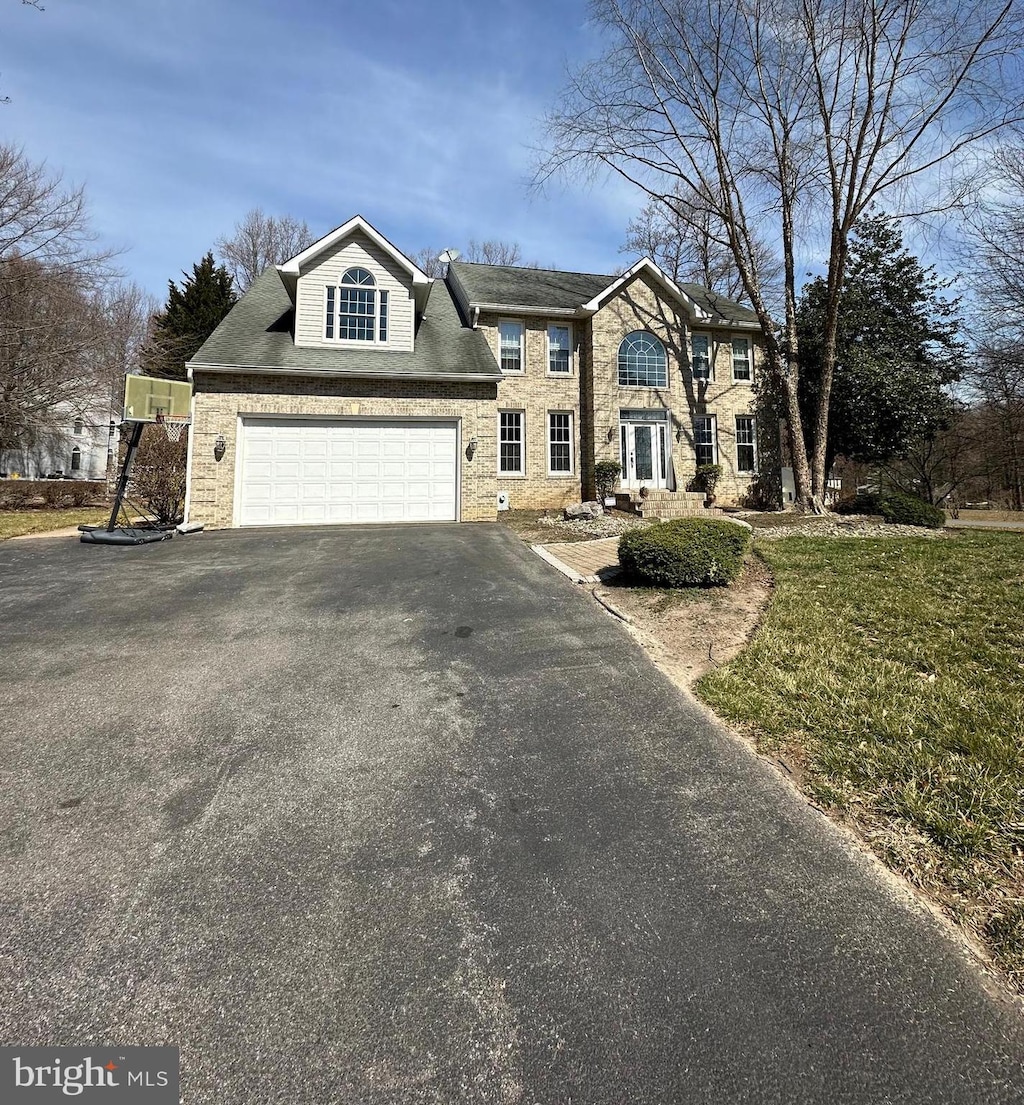 view of front facade featuring aphalt driveway, stone siding, and a garage