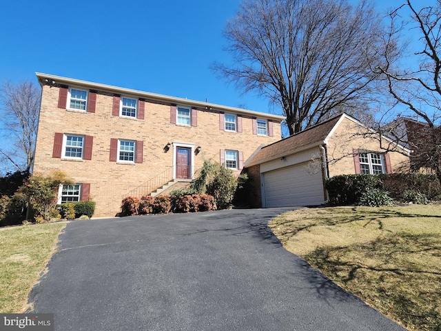 colonial home featuring an attached garage, brick siding, and driveway