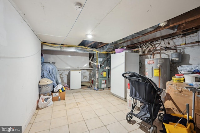 unfinished below grade area with refrigerator, heating unit, water heater, and freestanding refrigerator