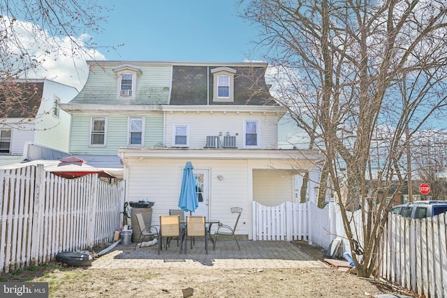 rear view of property featuring cooling unit, mansard roof, fence private yard, and a patio