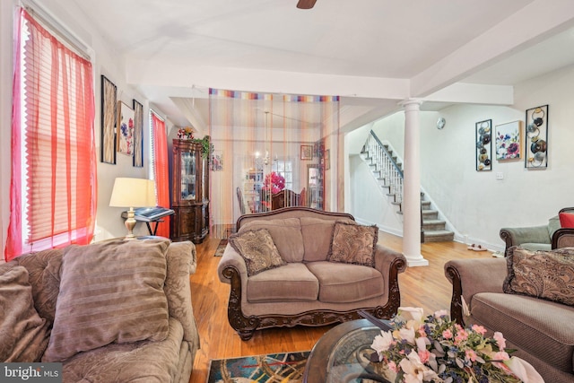 living area with stairway, baseboards, ornate columns, and wood finished floors