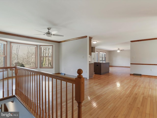 hall with baseboards, an upstairs landing, crown molding, and light wood finished floors