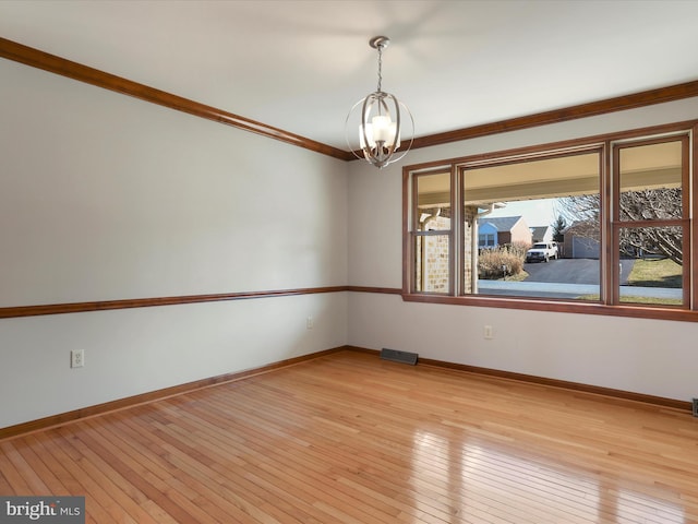 spare room featuring light wood finished floors, visible vents, baseboards, and an inviting chandelier