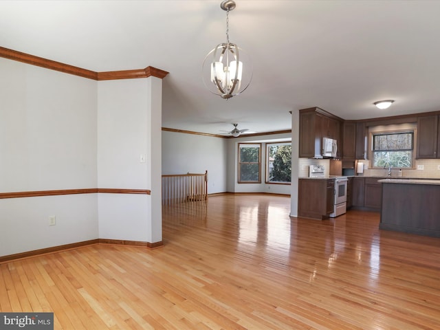 kitchen featuring white microwave, a sink, stove, light countertops, and open floor plan