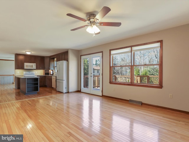 unfurnished living room featuring visible vents, baseboards, light wood-style floors, and a ceiling fan