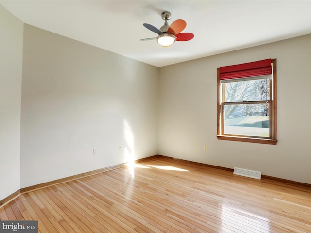 spare room featuring visible vents, ceiling fan, light wood-type flooring, and baseboards