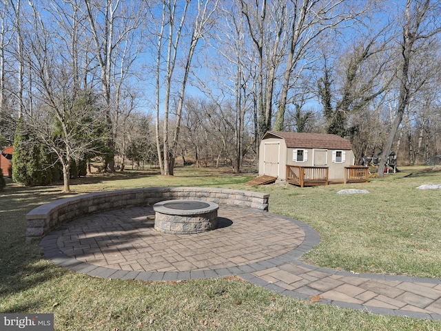 view of yard featuring an outbuilding, a patio, a shed, a fire pit, and a wooden deck