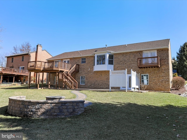 rear view of property with stairway, brick siding, a deck, and a lawn