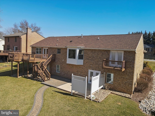 rear view of property with brick siding, a shingled roof, stairway, a yard, and a patio