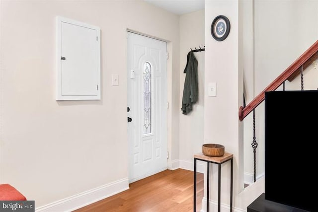 entryway with electric panel, stairs, baseboards, and wood finished floors