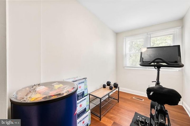 workout area featuring wood finished floors, visible vents, and baseboards