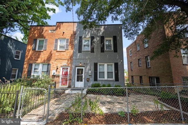 townhome / multi-family property with brick siding and a fenced front yard