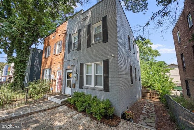 view of front of home with fence, brick siding, and crawl space