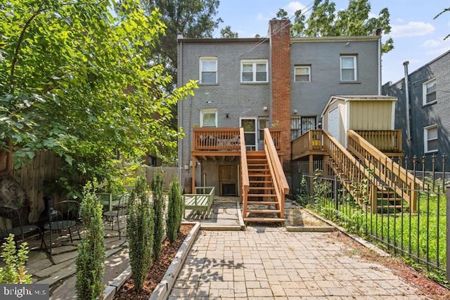 rear view of house featuring a patio, stairway, fence, a wooden deck, and brick siding