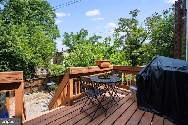 wooden deck featuring a grill, outdoor dining area, and fence