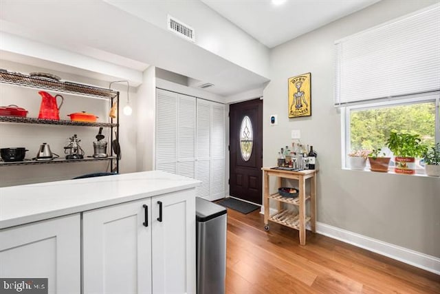 interior space with light wood finished floors, visible vents, and baseboards