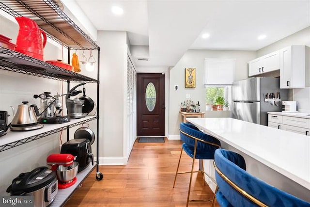 kitchen featuring baseboards, freestanding refrigerator, light countertops, white cabinets, and light wood-type flooring