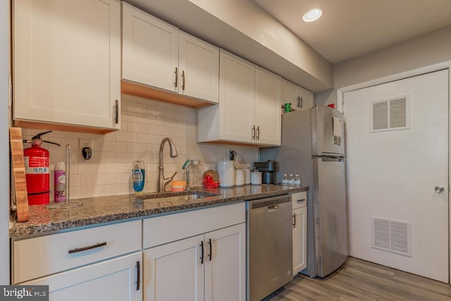 kitchen featuring visible vents, white cabinets, stainless steel appliances, and a sink