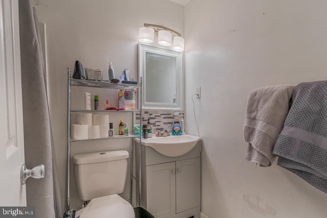 bathroom featuring vanity, toilet, and tasteful backsplash