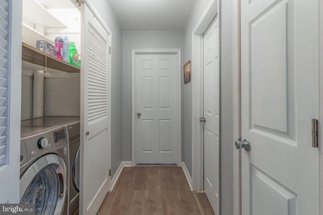 washroom featuring washer and clothes dryer, laundry area, baseboards, and wood finished floors