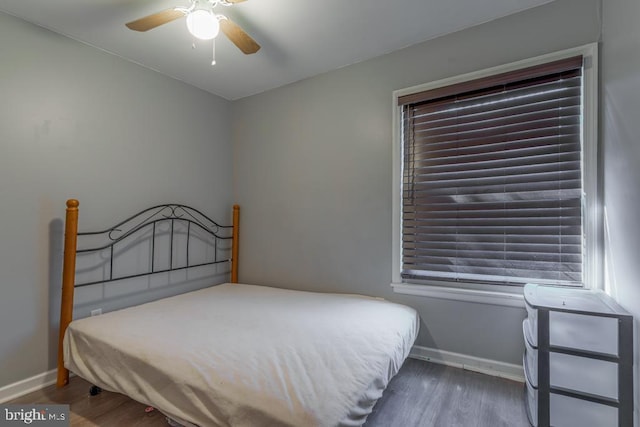 bedroom with multiple windows, baseboards, wood finished floors, and a ceiling fan