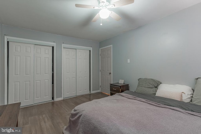 bedroom with a ceiling fan, wood finished floors, and two closets