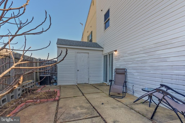 rear view of property with a patio, roof with shingles, central AC unit, and fence