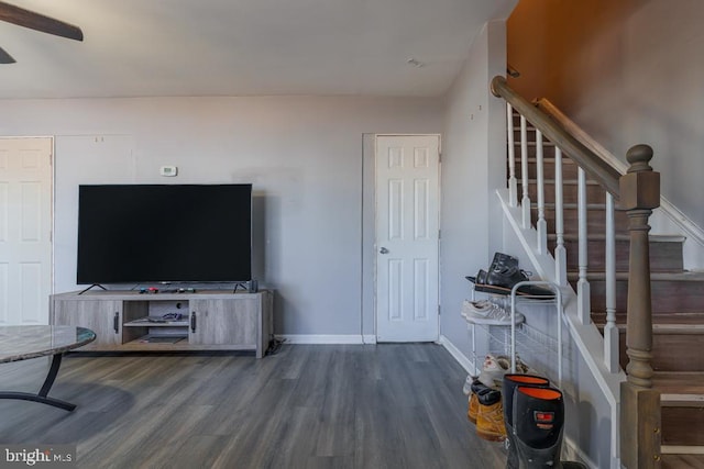 unfurnished living room featuring stairs, baseboards, and wood finished floors