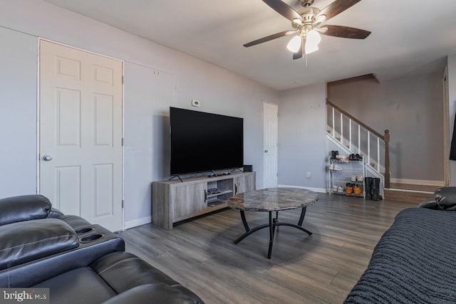 living area with a ceiling fan, stairway, wood finished floors, and baseboards