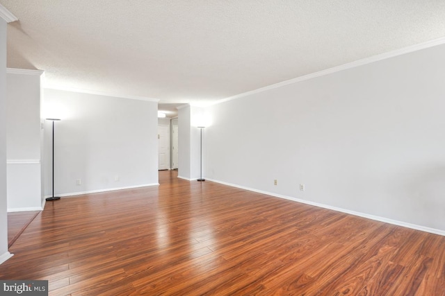 spare room featuring hardwood / wood-style flooring, baseboards, and ornamental molding