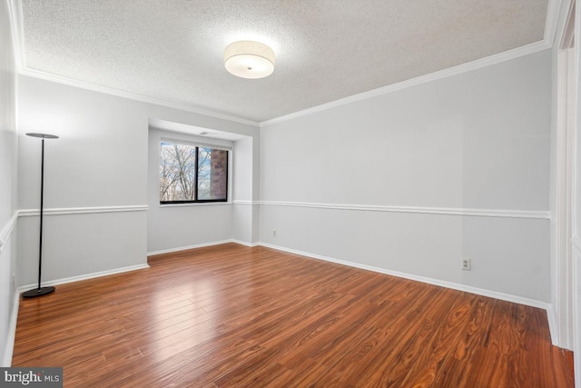 spare room with a textured ceiling, wood finished floors, baseboards, and ornamental molding