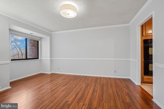 unfurnished room with baseboards, a textured ceiling, wood finished floors, and ornamental molding