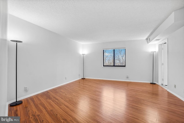 empty room featuring visible vents, wood finished floors, baseboards, and a textured ceiling