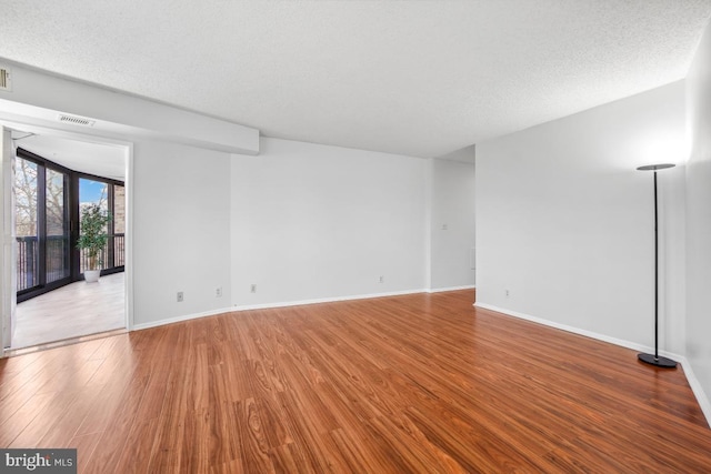 interior space featuring visible vents, baseboards, a textured ceiling, and wood finished floors