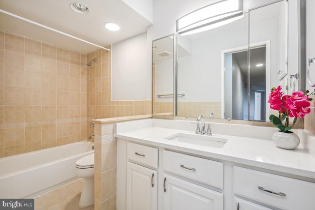 bathroom featuring vanity, shower / bath combination, tile patterned floors, toilet, and tile walls