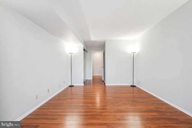 spare room featuring baseboards and wood finished floors