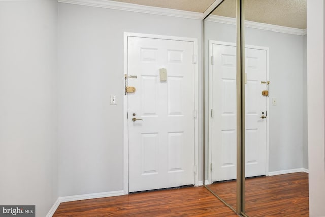 foyer entrance featuring dark wood-style floors, a textured ceiling, crown molding, and baseboards