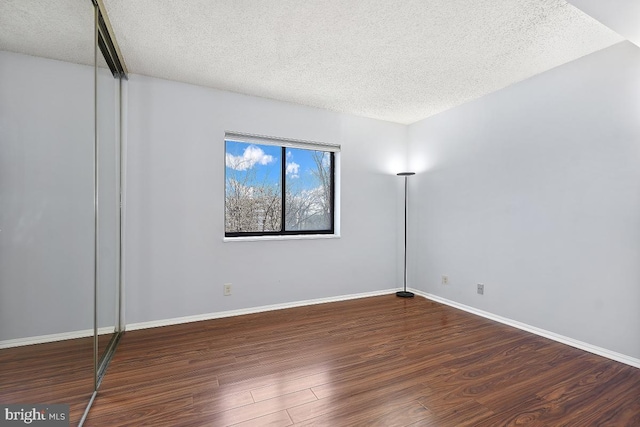 empty room featuring wood finished floors, baseboards, and a textured ceiling